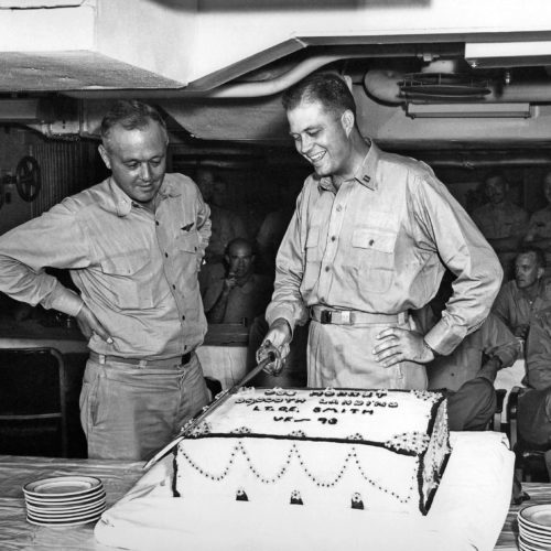CAPT. Frank A. Brandly, USN, C. O. of Hornet looks on admiringly as LT. Carl E. Smith, USN, VF-93 cuts cake baked to celebrate his landing on 1 October 1954 making the 30,000th landing on Hornets (CV-12) and (CVA-12).