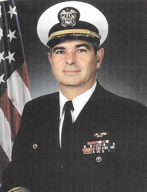 Portrait of US Navy Captain Dodge in uniform with American flag.