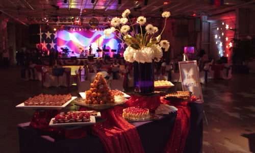 Dessert table with flowers at event with stage and live band.