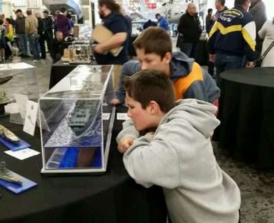 Children examining a ship model at USS Hornet Museum event.