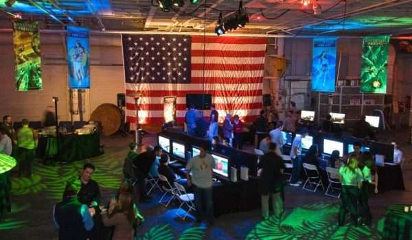 Event attendees at gaming station with American flag backdrop.