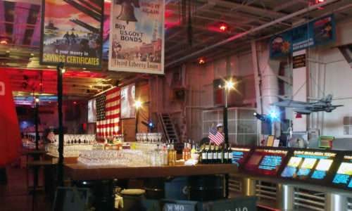 Bar setup with vintage posters and American flag backdrop.