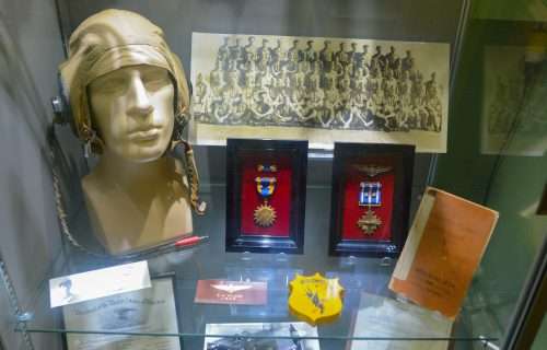 Display of pilot helmet, medals, and historical photo at museum.