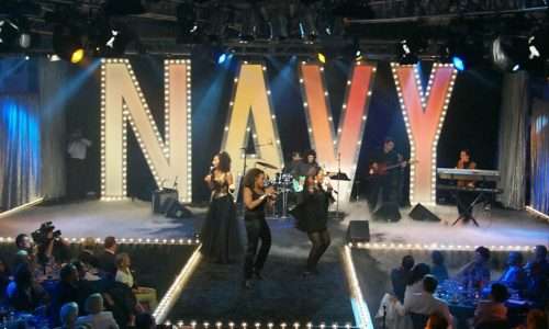 Live musical performance with large NAVY sign on stage.