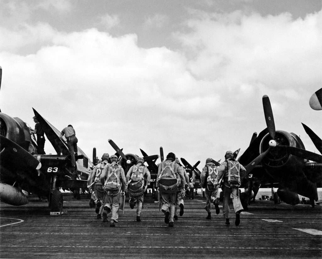 black and white photo of military pilots walking towards planes