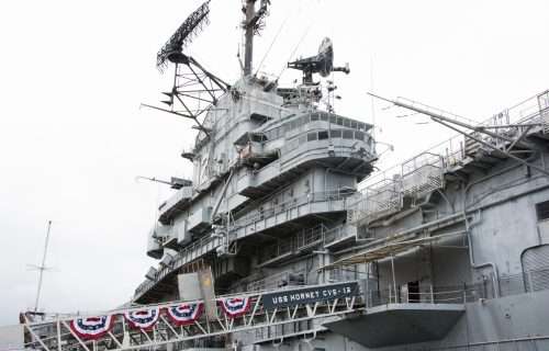 USS Hornet aircraft carrier side view with radar towers and bunting.