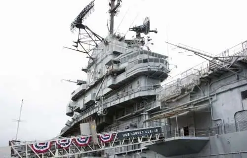 USS Hornet aircraft carrier side view with radar towers and bunting.