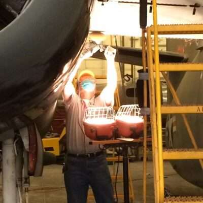 A man wearing a mask is fixing an airplane.