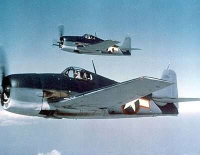 Two U.S. Navy Hellcat fighter planes in flight during WWII.