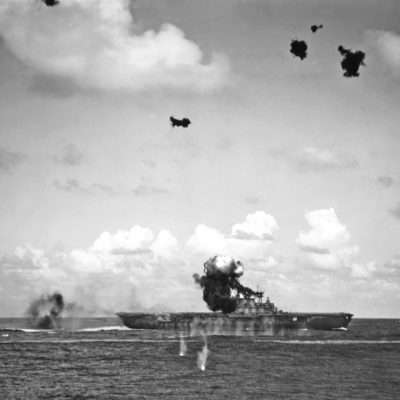 A Japanese Aichi D3A1 Val Dive Bomber crashes into the signal bridge of Hornet during the first attack of the Battle of Santa Cruz Islands. Photograph taken from USS Pensacola (CA-24).