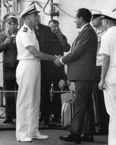 President Nixon shaking hands with Captain Seiberlich on the USS Hornet deck, photographers in the background.