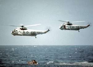 Navy helicopter 66 in flight above the ocean during a recovery operation.