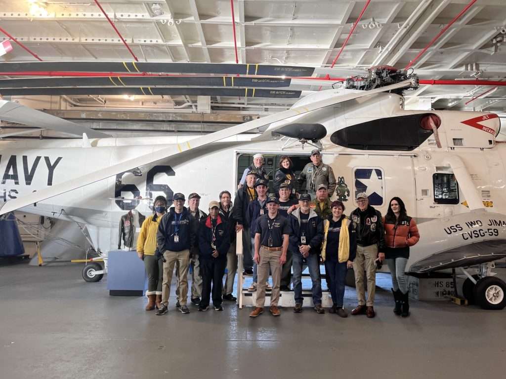 a group of volunteers posing in front of a helicopter